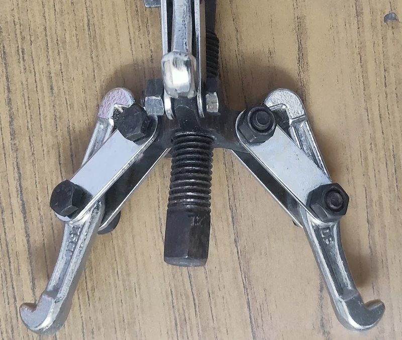Ściągacz do łożysk z dwoma szczękami i śrubą dociskową leżący na drewnianym blacie